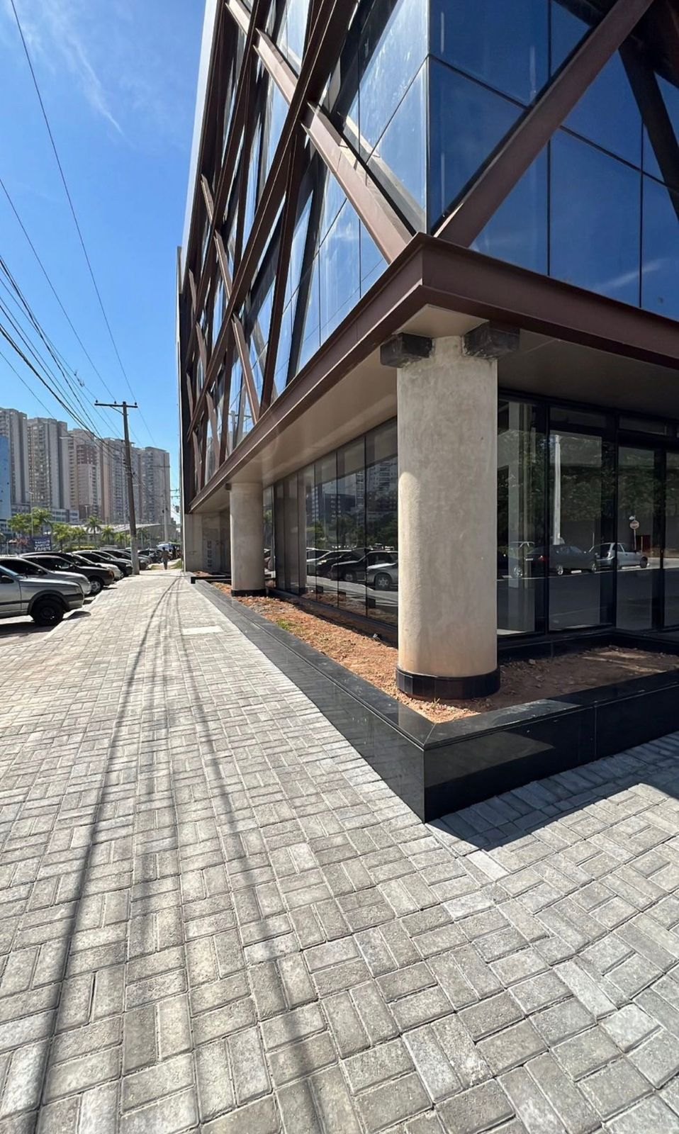Calçada em piso intertravado ao longo da fachada de vidro de um prédio comercial