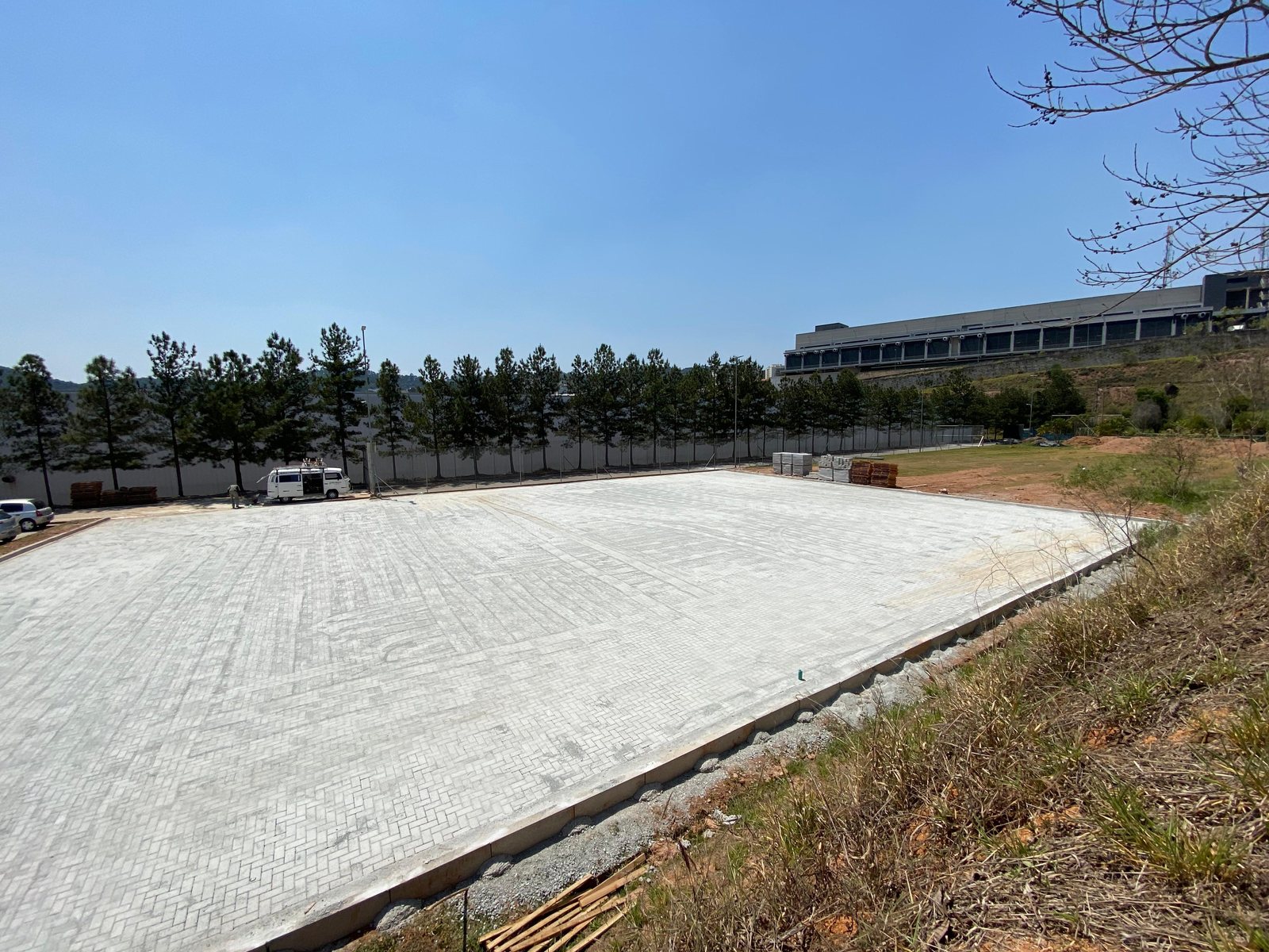 Vista lateral de um pátio grande com piso intertravado concluído e guias nas bordas